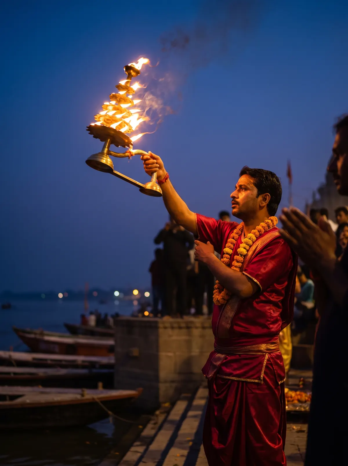 A priest raising the tiered flame lamp at the evening Ganga aarti